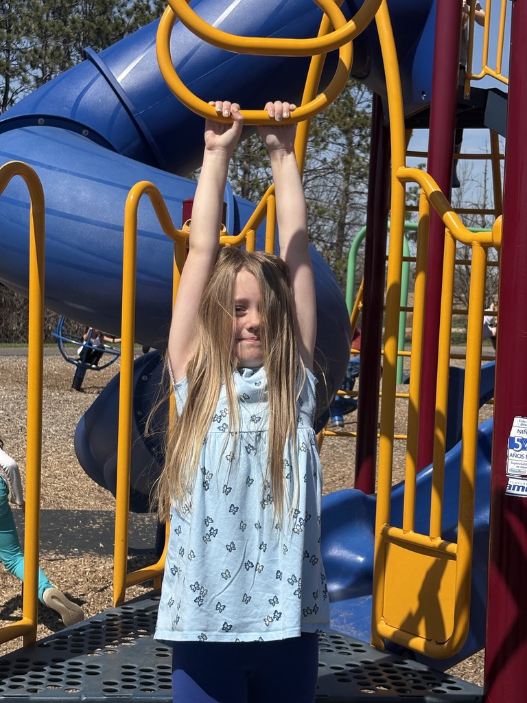 Little girl hanging from the monkey bars.
