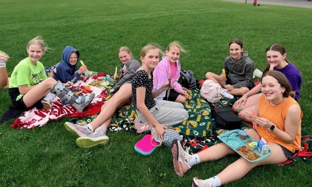 Students smiling with their lunch outside.