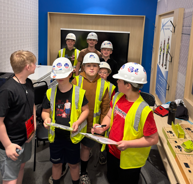 A group of students in construction vests and helmets.