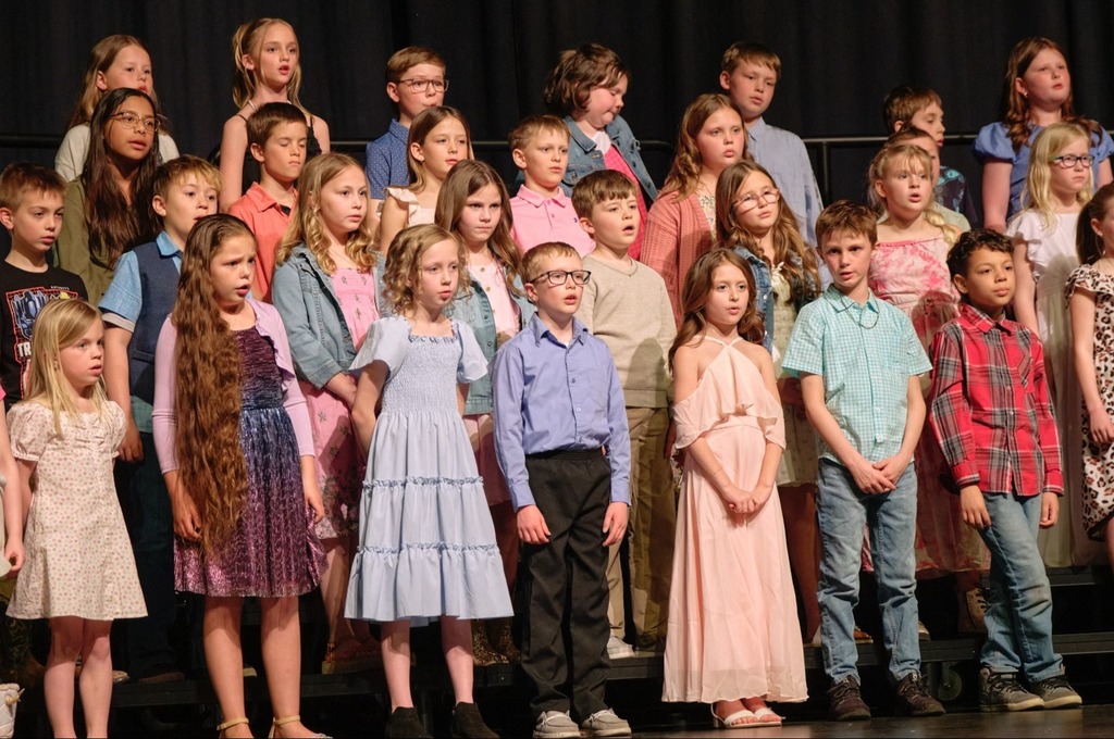 Students standing and smiling at the concert, some are singing.