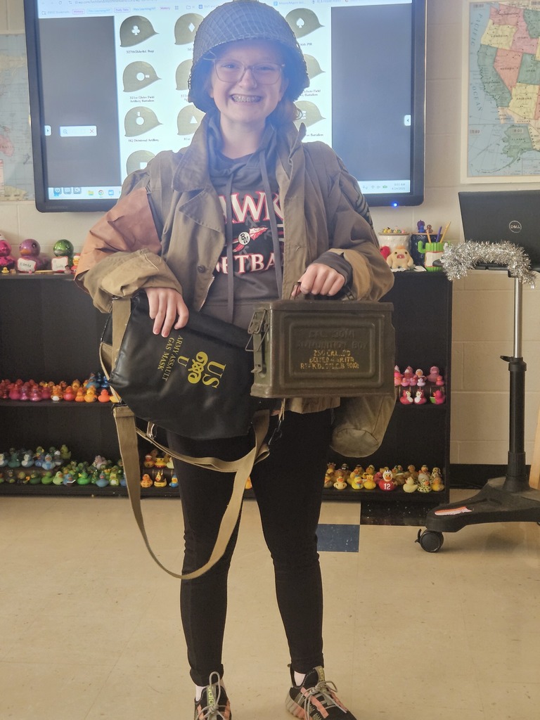 A student smiling and holding WWII reenactment gear
