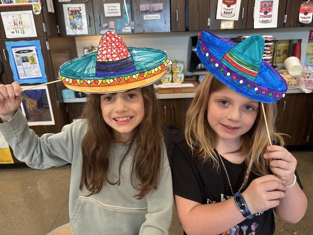 Two girls holding up the sombreros they designed.