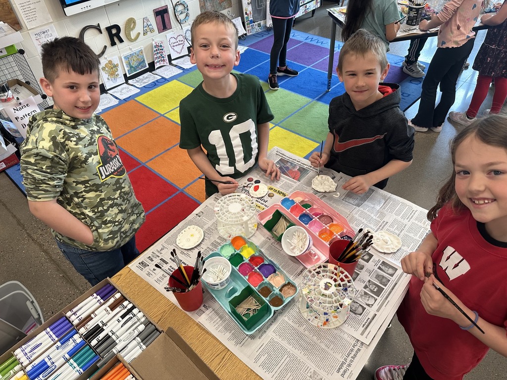 Three boys and a little girl smiling and painting.