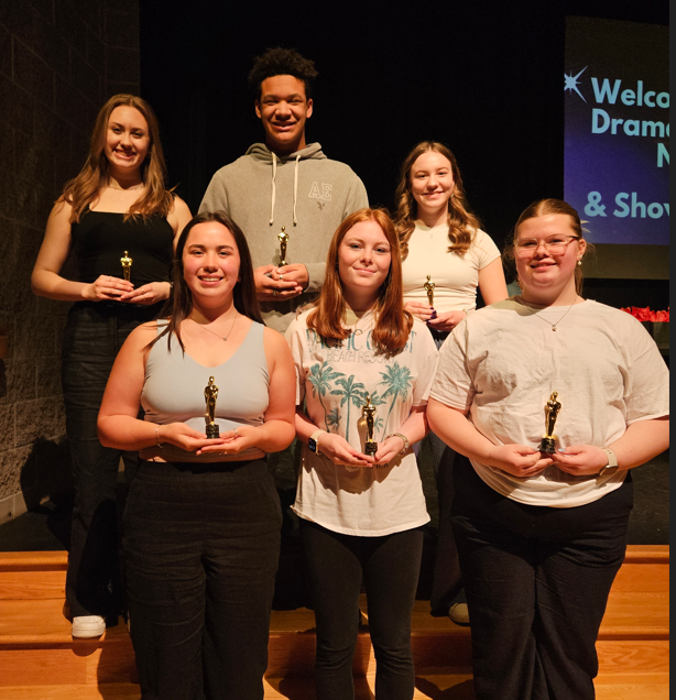 Students smiling with their awards on stage