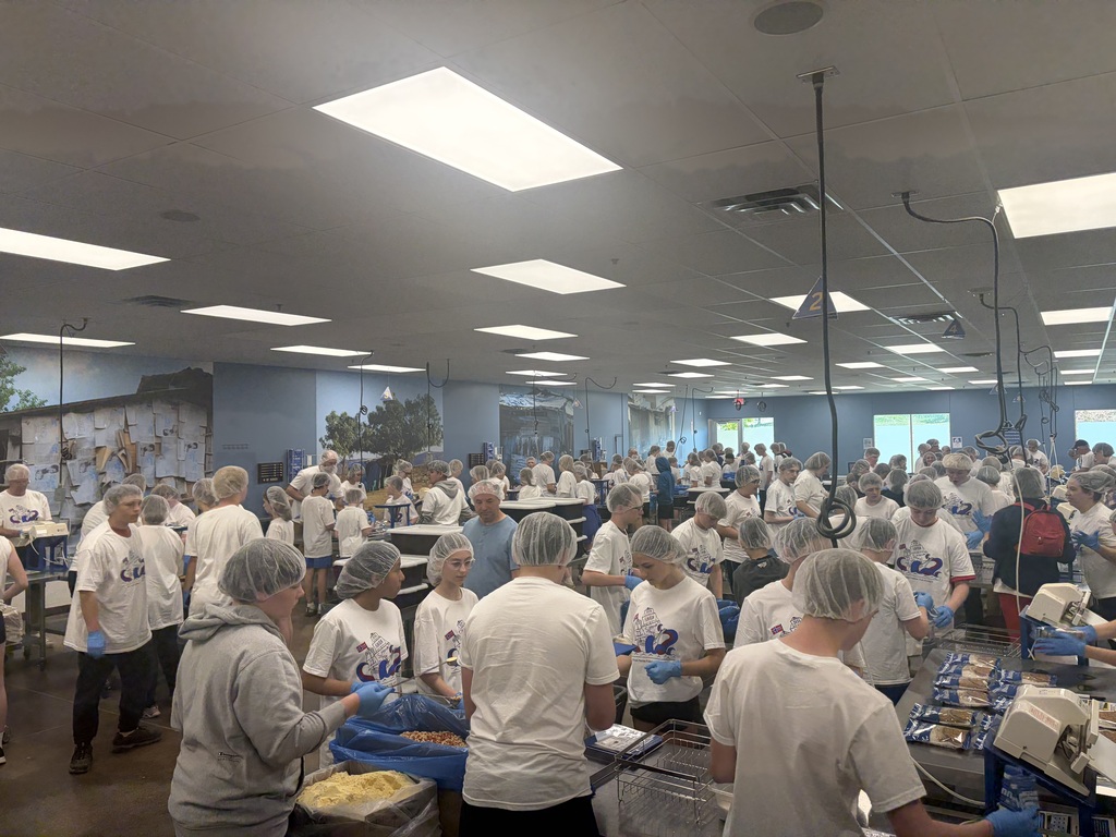 Large room filled with volunteers packing meals.