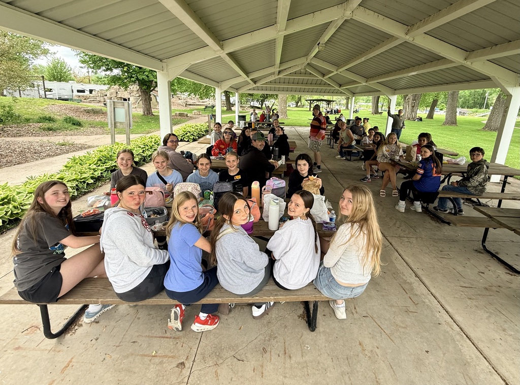 Students and chaperones at picnic tables enjoying lunch.