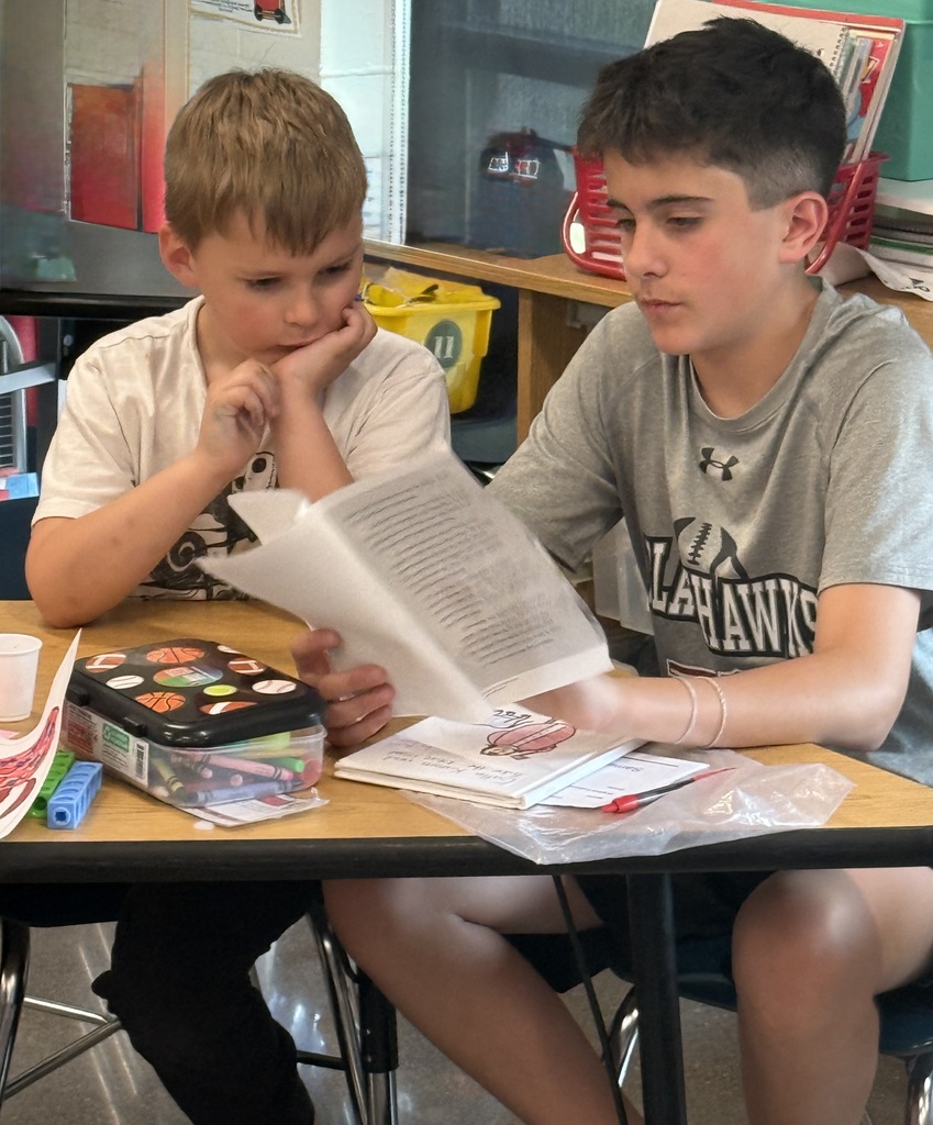 A 6th grade boy reading to a kindergartner.