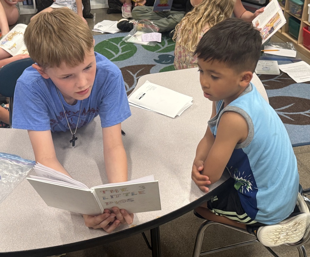 Two boys sitting at a table reading.