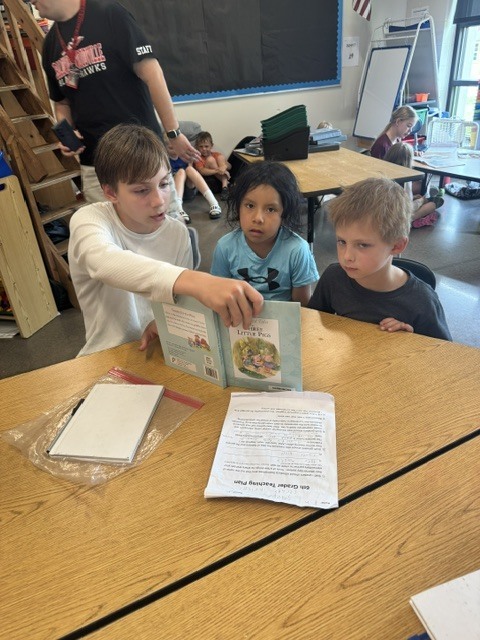 Student reading to two students.