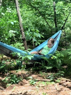 A student relaxing and reading in a hammock.