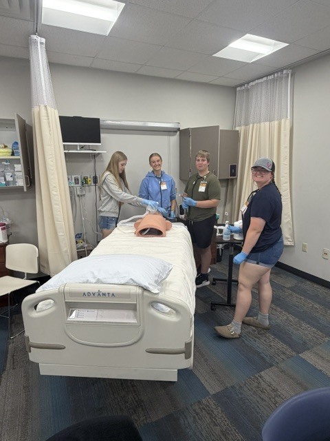Students smiling while  working on a simulated patient.