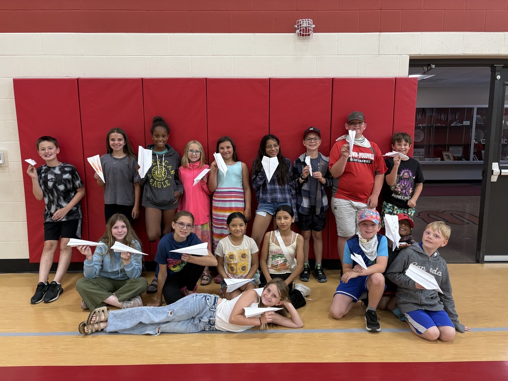 Students smiling in the gym holding up their paper airplanes they created!