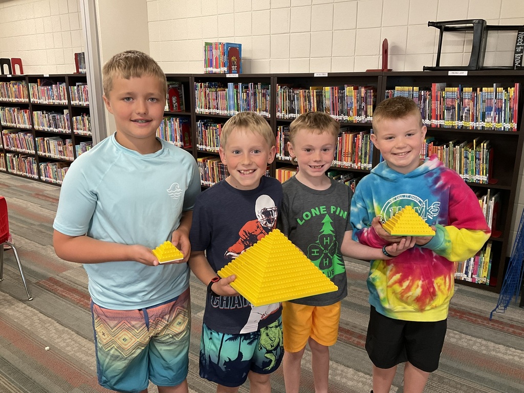 A group of four boys showing off the pyramids they made out of legos.