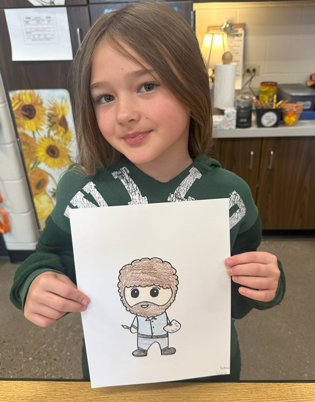 A young girl with brown hair wearing a green hoodie holding up a colored drawing of a cartoon Bob Ross holding a paintbrush and paint palette.