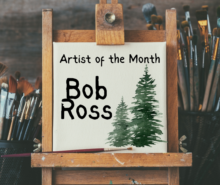 A small square canvas resting on a wooden tabletop easel with paintbrushes surrounding it in the background. The text on the canvas reads "Artist of the Month Bob Ross" next to an illustration of two green pine trees.