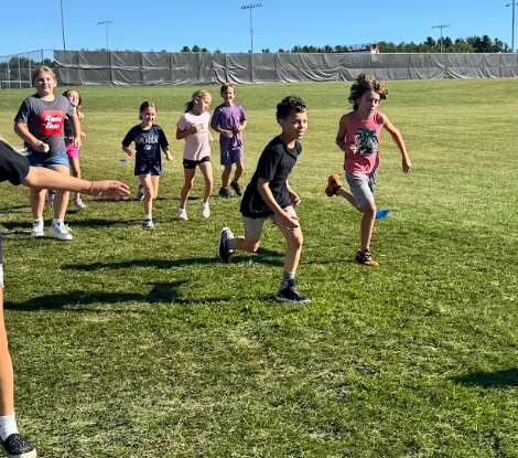 Students running and smiling in the grass.