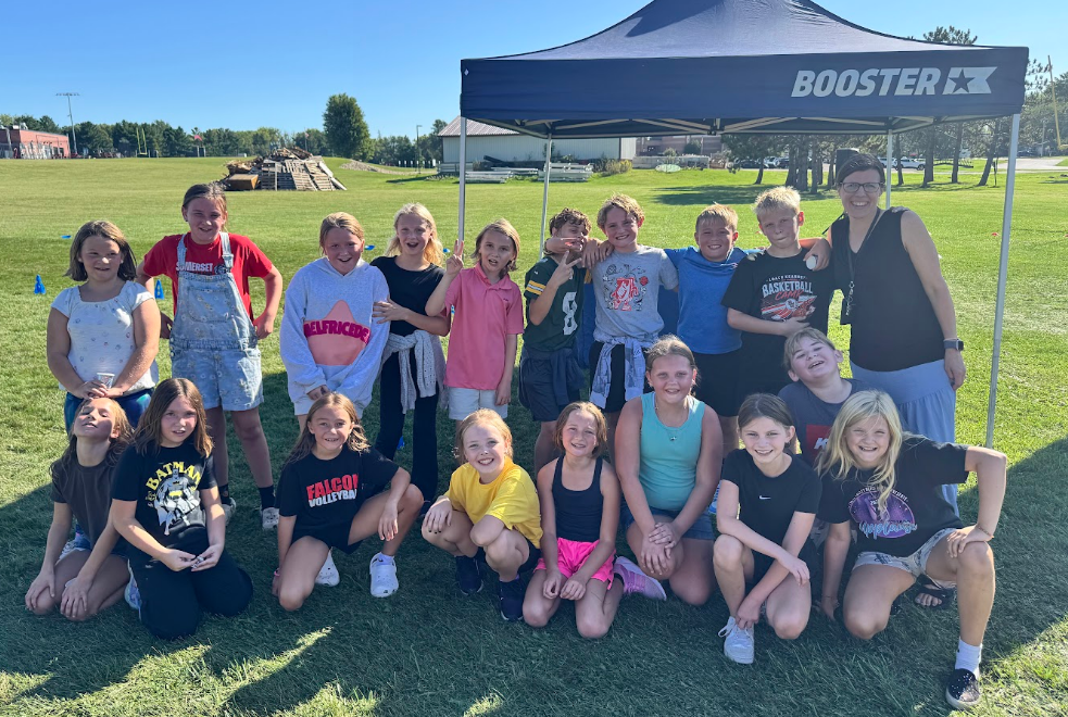 Class smiling outside under a tent that says BOOSTER.
