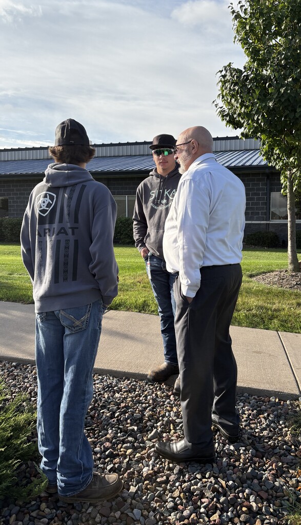 Two students standing outside talking to a business leader.