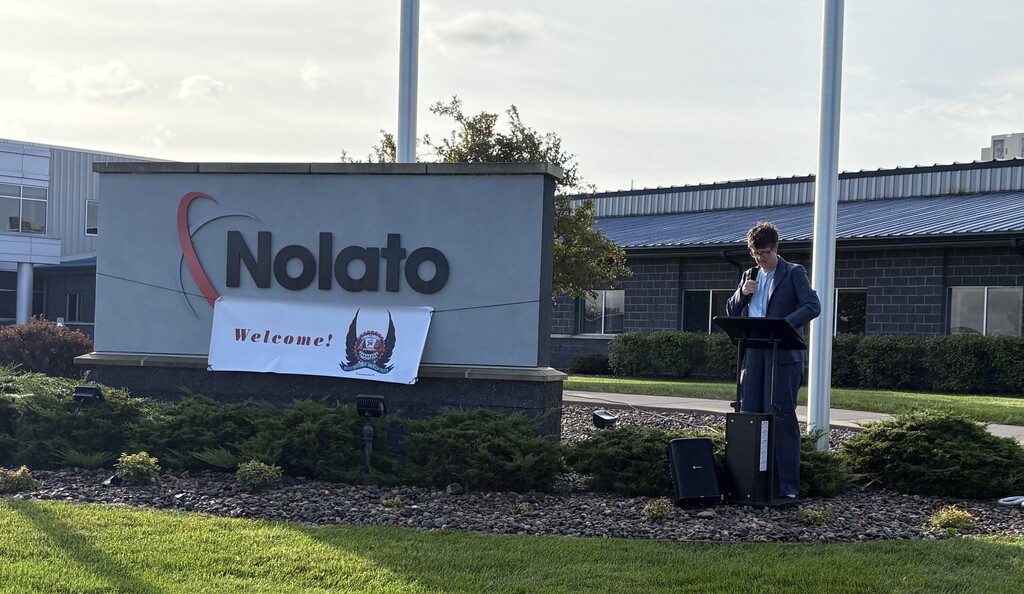Dr. Jill Underly speaking outside at a podium with a Nolato sign.