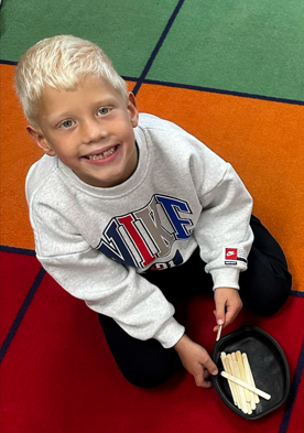 A young boy sitting on a colorful carpet grid