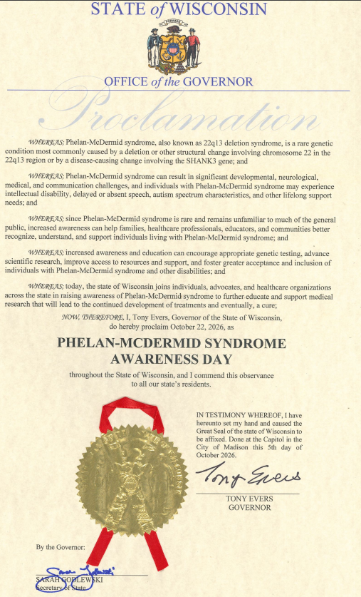 An official proclamation document from the State of Wisconsin, Office of the Governor, Tony Evers, with a gold seal and red ribbon at the bottom. The document officially proclaims October 22, 2026, as Phelan-McDermid Syndrome Awareness Day throughout the State of Wisconsin.