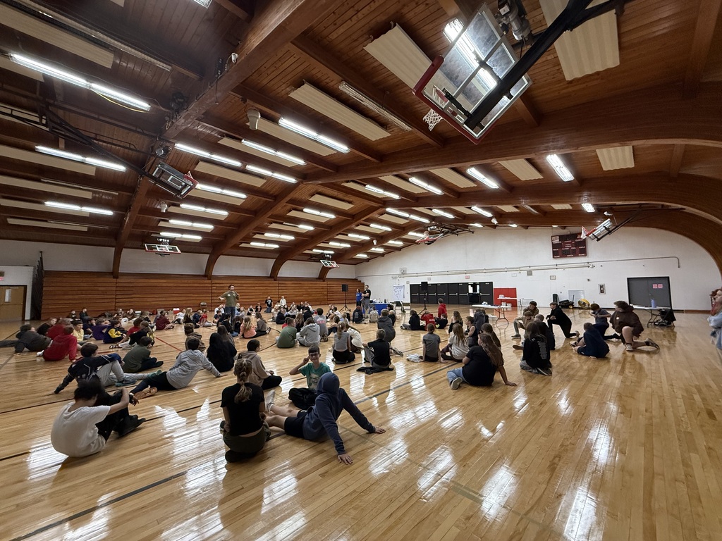 Seventh grade students sitting on the gymnasium floor in small groups during an interactive Youth Frontiers Courage Retreat activity.