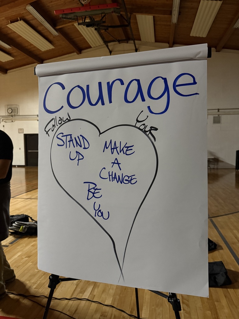 An easel display board showing a handwritten heart graphic labeled "Courage" with inspiring phrases including "Follow your heart," "Stand up," "Make a change," and "Be you".