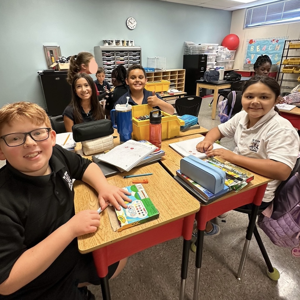 Students at a desk smiling 