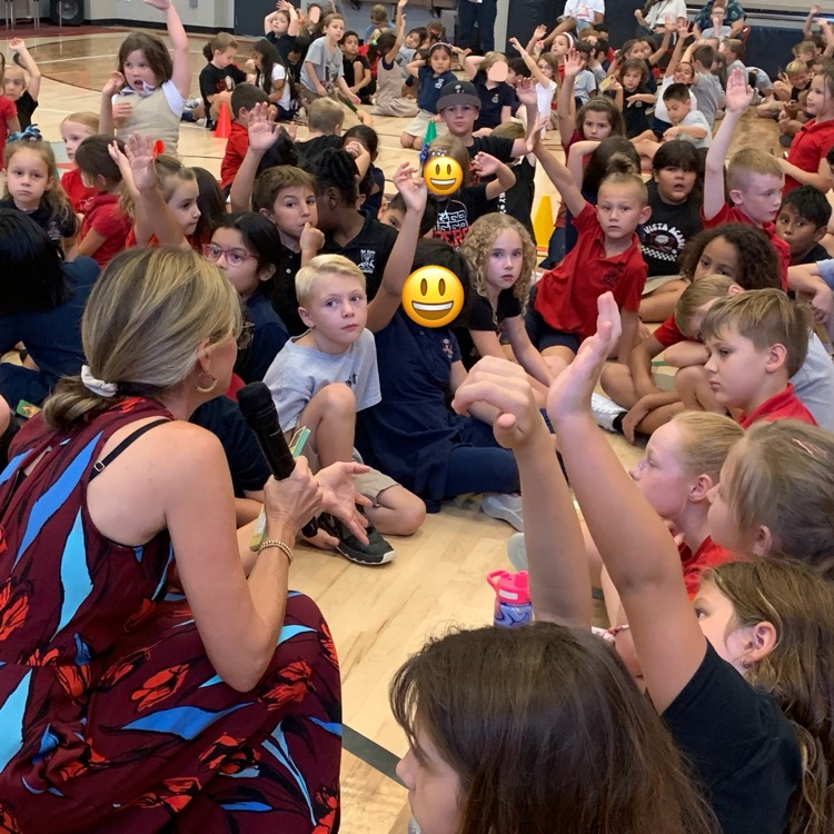 kids raising their hand at an assembly 