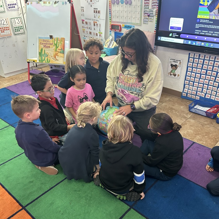 children with teacher gathered around a globe