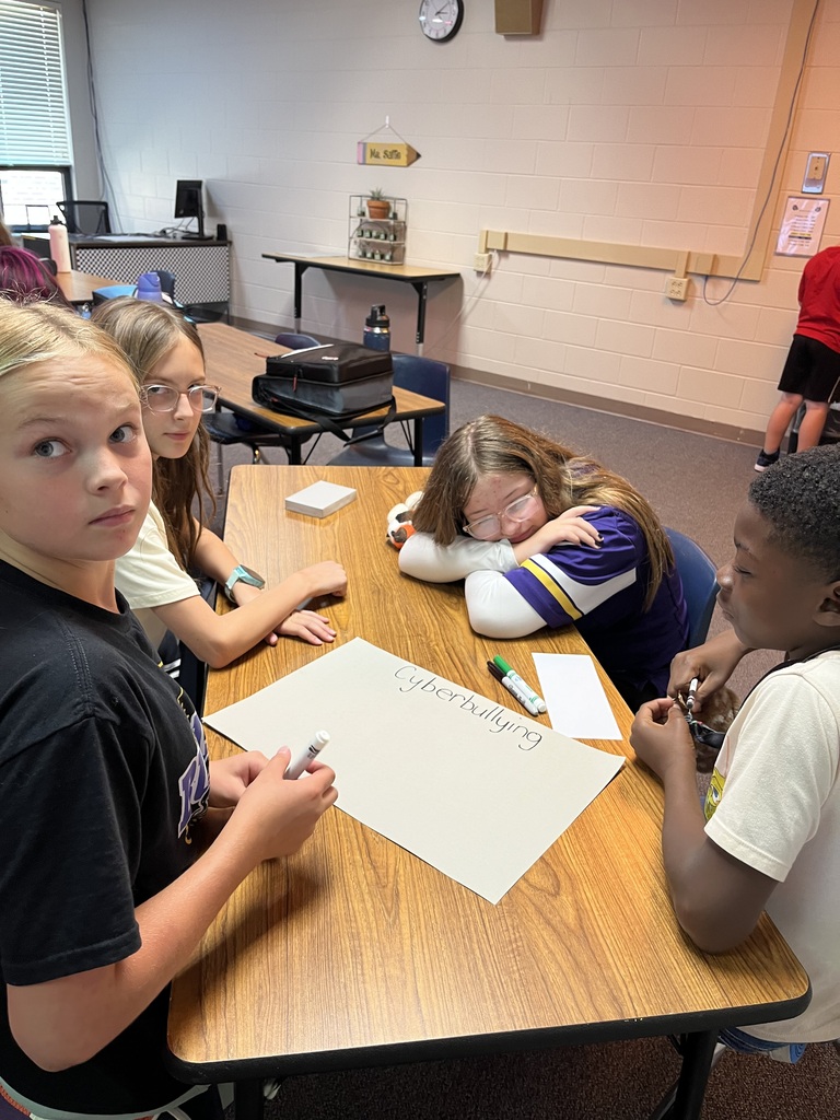 Students sitting around a table working in a classroom on digital citizenship