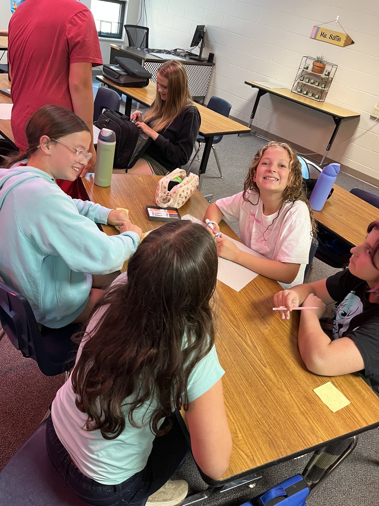 Students sitting around a table working in a classroom on digital citizenship