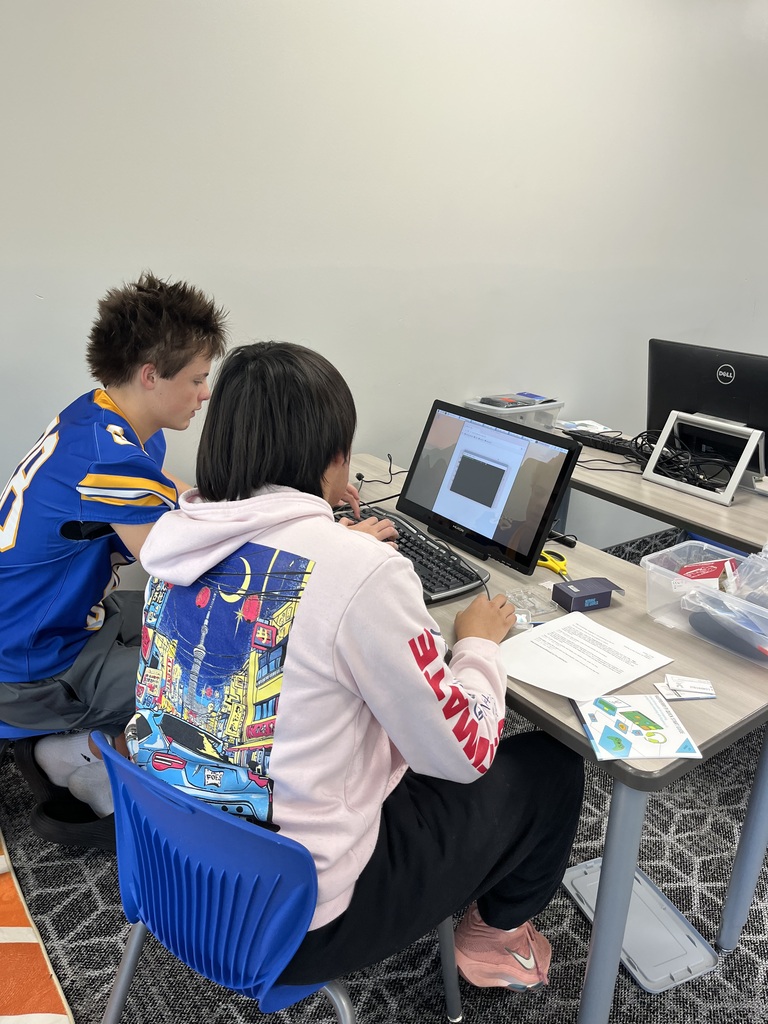 Two students collaborate at a computer workstation, examining programming software and working together on a Raspberry Pi technology project.