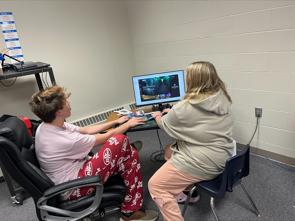 Two students sit together at a computer workstation, using a keyboard and mouse while participating in a video gaming activity.
