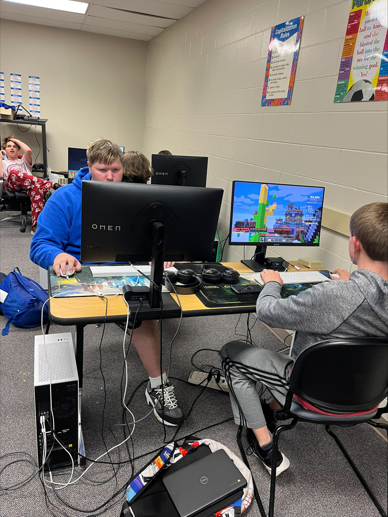 Students participate in computer gaming at multiple workstations. One monitor displays Minecraft gameplay while students use gaming computers, keyboards, and mice.