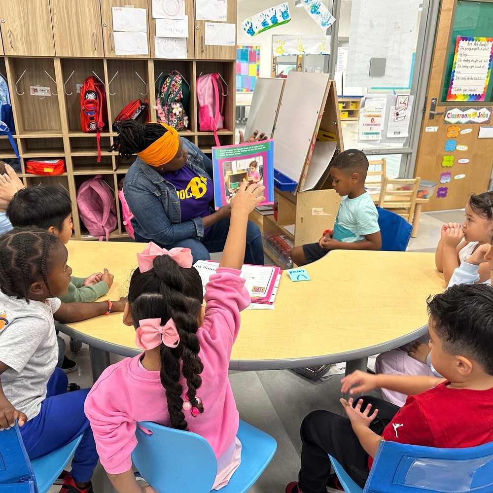 teacher having a lesson with students at a table with books