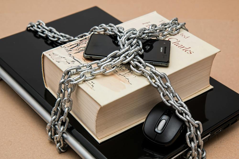laptop, book, and phone chained up to depict privacy of data