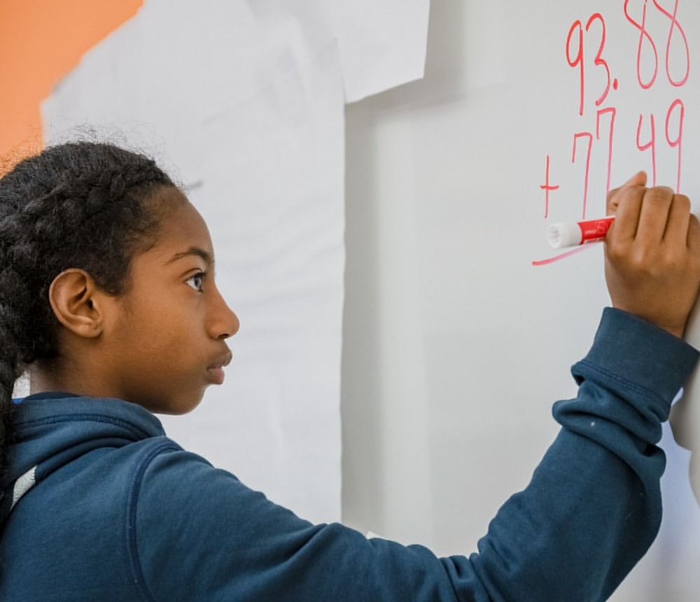 student at whiteboard working a math problem