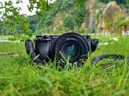 camera lying in the grass with a natural landscape in the background