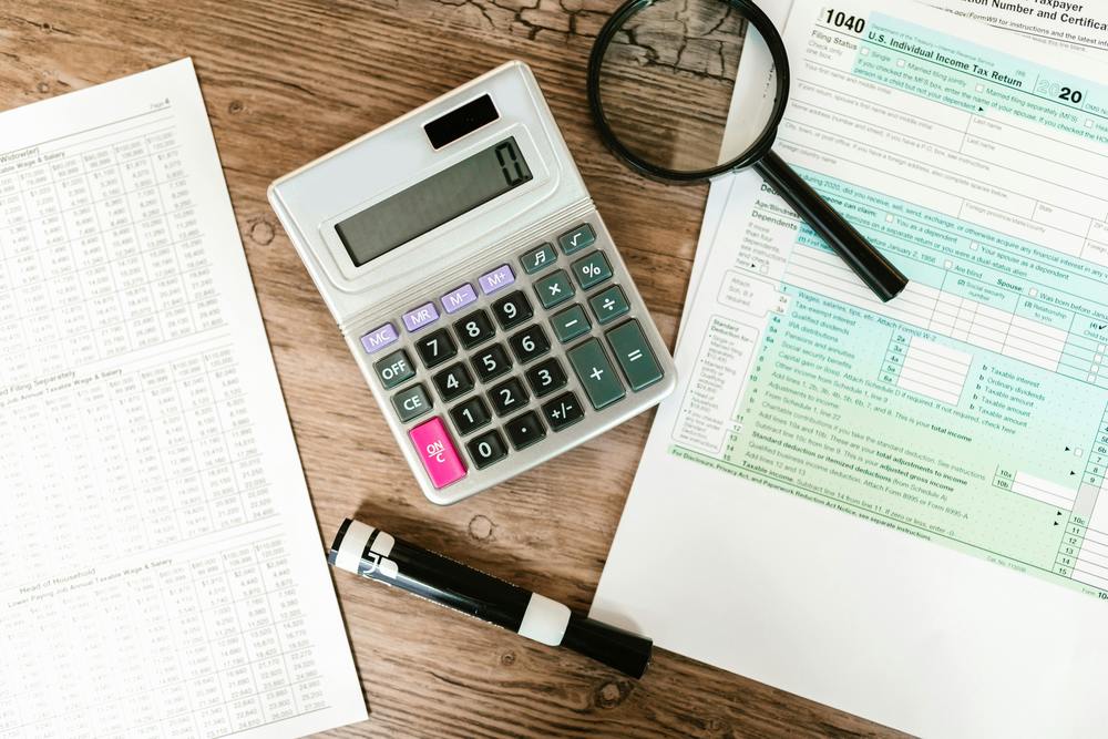 calculator, marker, and magnifying glass sitting on a table with financial documents