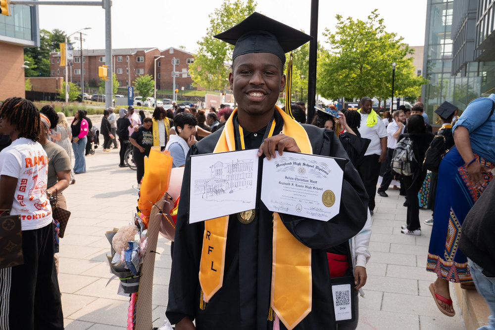 Student poses with diploma at Reginald F. Lewis High School graduation