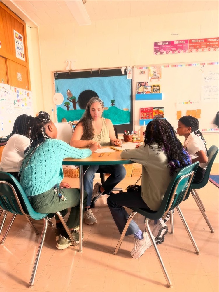 teacher working with students at a table