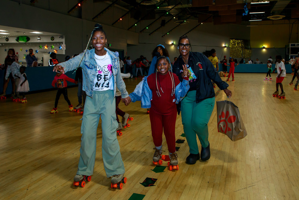 A family holds hands while skating through the rink at a back to school skate night
