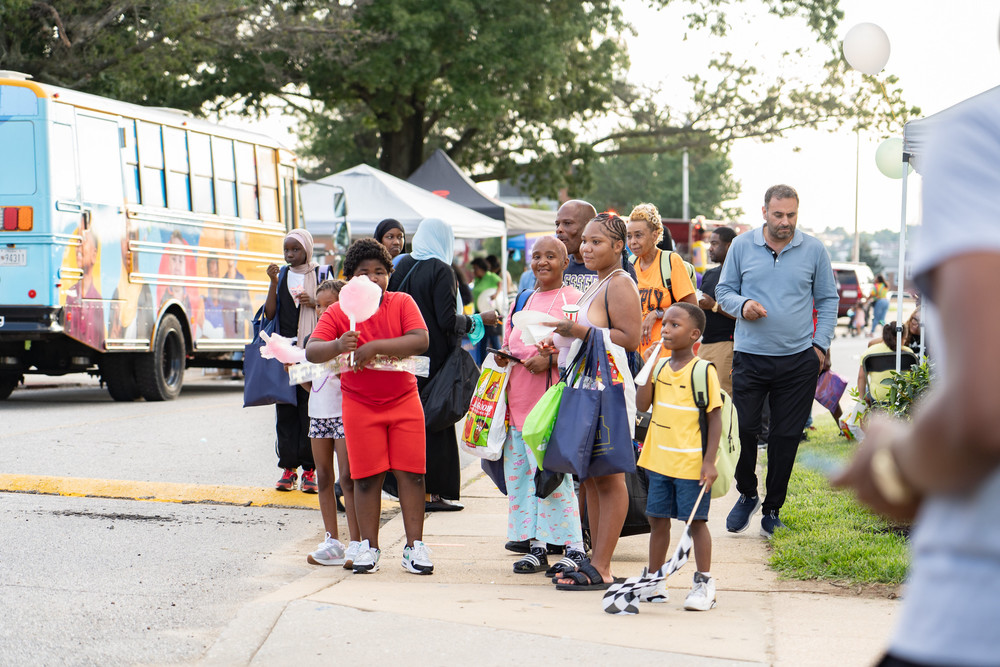 A family enjoy a performance and eat cotton candy while attending National Night Out