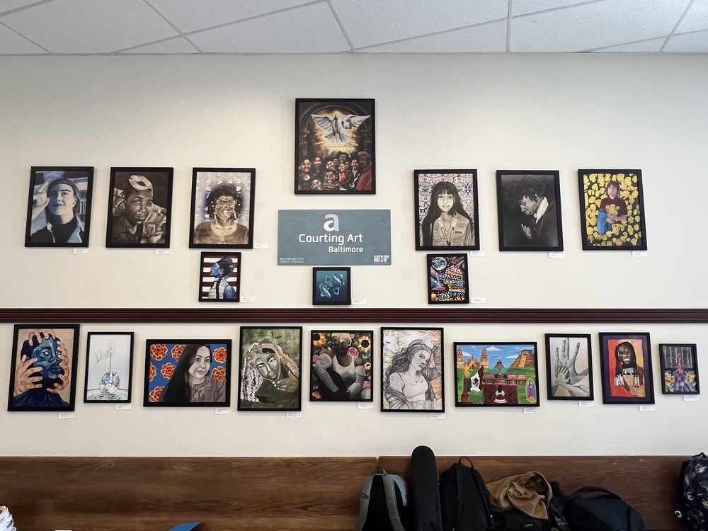 A wall of artwork with a sign that says "Courting Art"