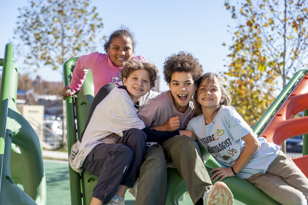 Kids smiling at the camera while playing on the playground
