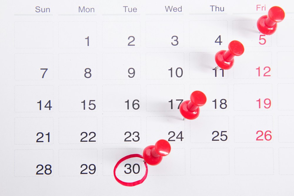 calendar with circled dates and red thumbtacks pinned across it
