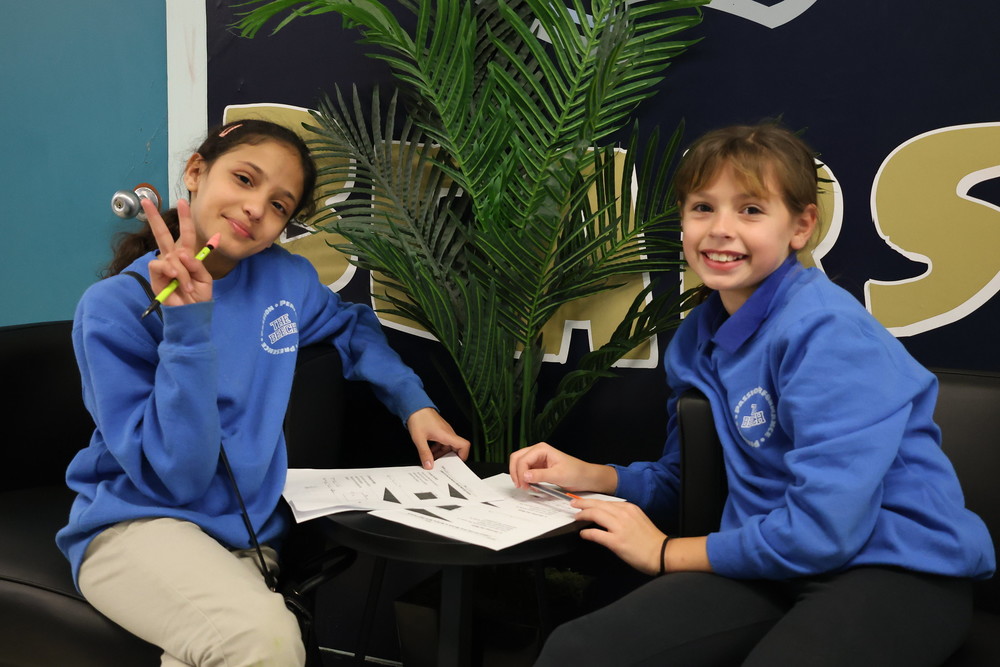 Two students sitting at a table smiling 