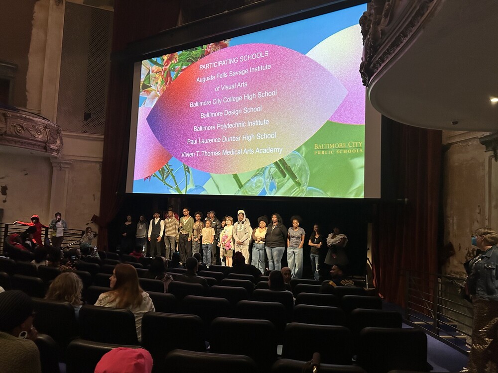 A movie screen with students assembled in front of it at the Parkway Theater