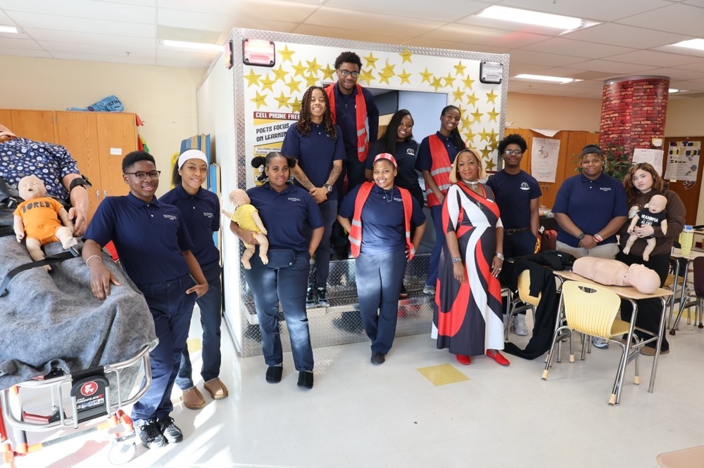 EMT Class at Dunbar high school poses for a group picture in front of their ambulance simulator.